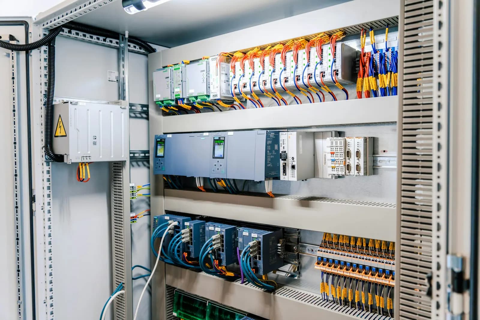 Quadro elettrico industriale aperto con moduli, morsettiere e cablaggi colorati